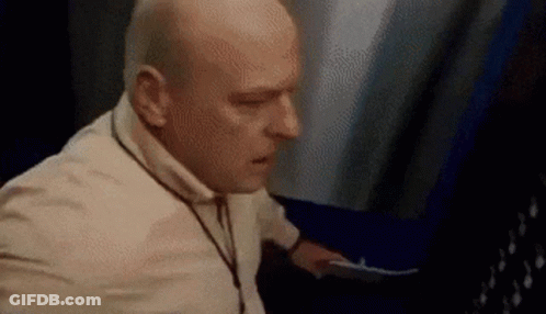 Bald Man In White Shirt Standing Next To Woman GIF