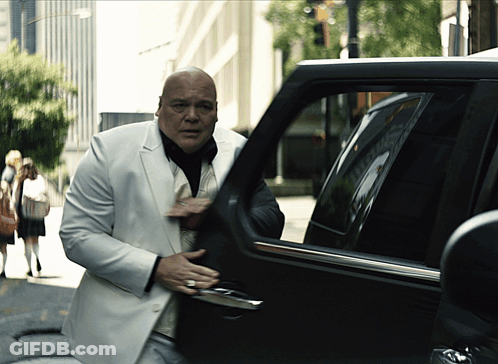 Bald Man In White Suit Exiting Black Car GIF
