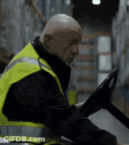 Bald Man In Yellow Safety Vest Driving Forklift GIF