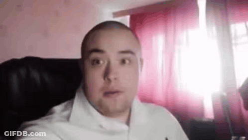 Bald Man Looking At Camera By Window GIF
