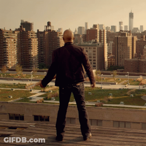 Bald Man On Rooftop Overlooking City Skyline GIF