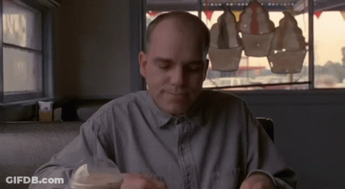 Bald Man Sitting At Table In Diner GIF