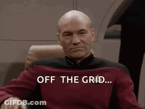 Bald Man Sitting In Chair With Off The Grid Shirt GIF