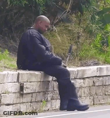 Bald Man Sitting On Brick Wall GIF