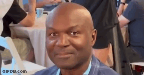 Bald Man Smiling At Table In Crowd GIF