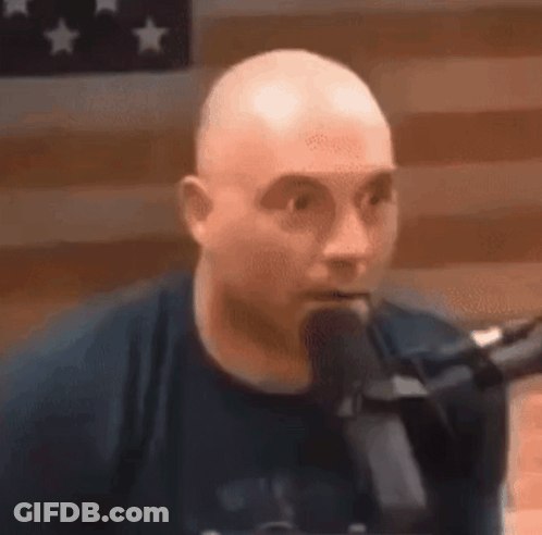 Bald Man Speaking Into Microphone Before American Flag GIF
