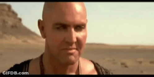 Bald Man Standing In Desert Looking At Camera GIF