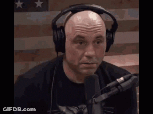 Bald Man Talking Into Microphone Near American Flag GIF