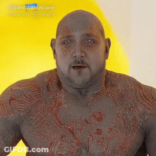 Bald Man With Beard And Chest Tattoos In Front Of Yellow Wall GIF