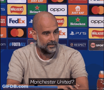 Bald Man With Beard Sitting In Front Of Manchester United Sign GIF