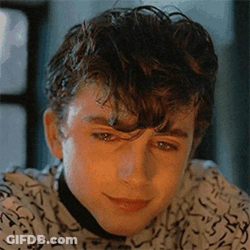 Bald Man With Chest Tattoo Looking At Another Man GIF