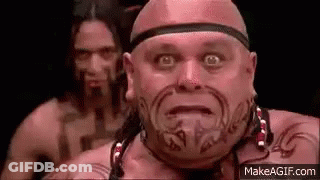 Bald Man With Face Tattoo In Front Of Another Bald Man GIF