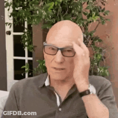 Bald Man With Glasses On Couch Hand On Forehead GIF
