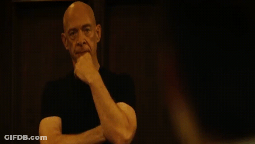 Bald Man With Mustache Looking At Camera In Dark GIF