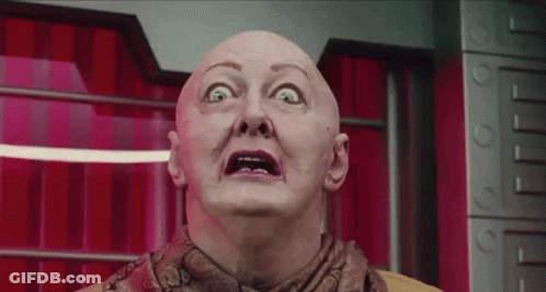 Bald Woman Making Funny Face In Front Of Red Curtain GIF