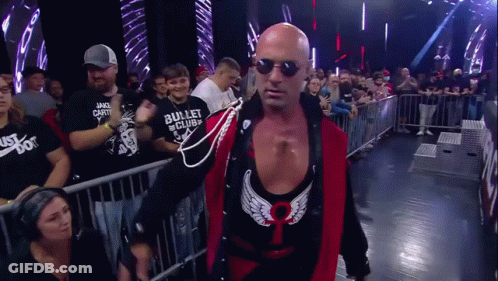 Bald Wrestler In Sunglasses And Red Vest Walking Through Crowd GIF