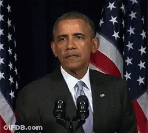 Barack Obama Is Giving A Speech In Front Of A Microphone In Front Of American Flags . GIF