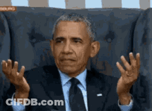 Barack Obama Is Sitting In A Chair With His Hands In The Air GIF