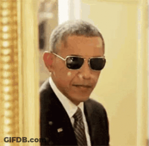 Barack Obama Is Wearing Sunglasses And A Suit And Tie While Peeking Out Of A Picture Frame . GIF
