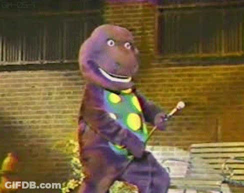 Barney The Dinosaur Is Holding A Microphone And Dancing In Front Of A Brick Building GIF