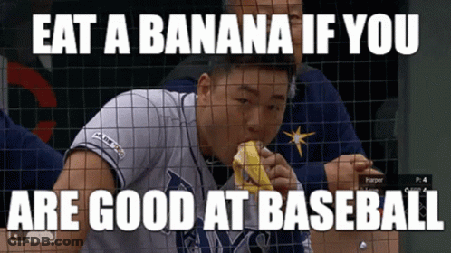 Baseball Player Eating Banana Behind Fence GIF