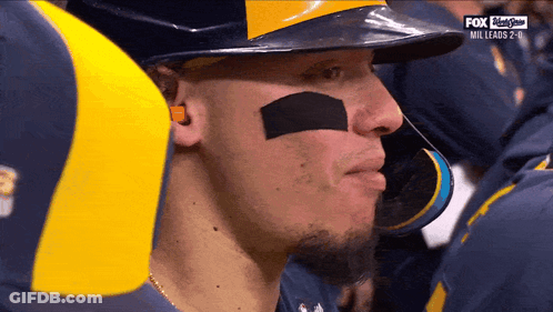 Baseball Player In Helmet And Ear Plugs Watching Fox GIF