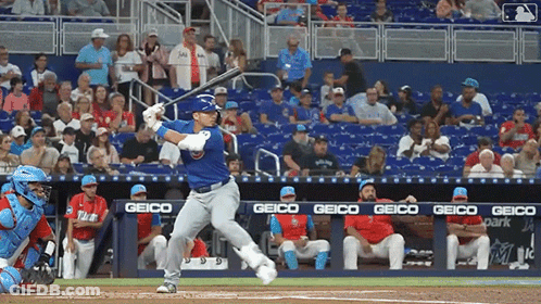 Baseball Player Swinging At Pitch With Geico Banner GIF
