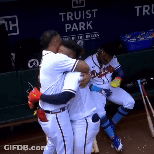 Baseball Players Hugging Each Other In Front Of A Sign That Says Truist Park GIF