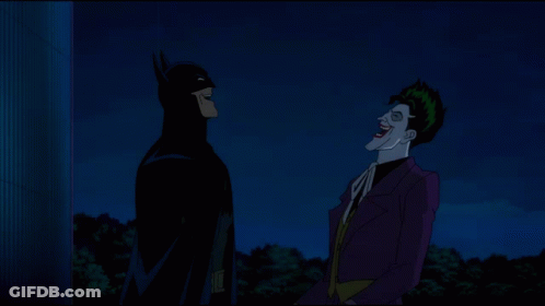 Batman And The Joker Standing Next To Each Other At Night GIF
