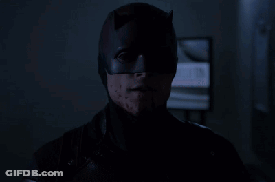 Batman Mask Man Stares At Camera In Dark GIF