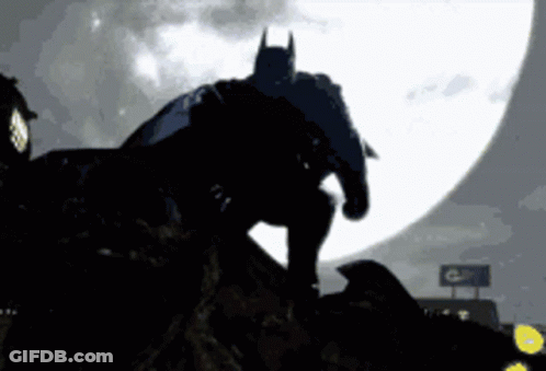 Batman Silhouette Standing On Rock In Front Of Full Moon GIF