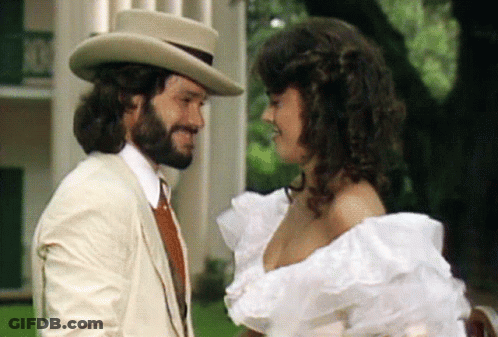 Bearded Man And Woman In White Dress Looking At Each Other GIF