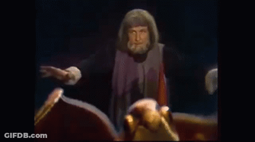 Bearded Man Beside Dragon Statue With Spread Wings GIF