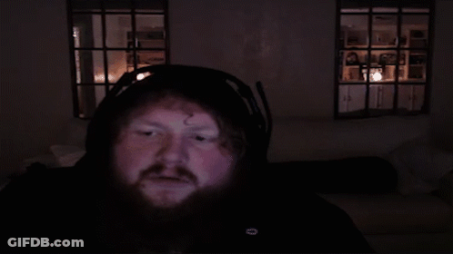 Bearded Man Headphones Looking At Camera Dark Room GIF