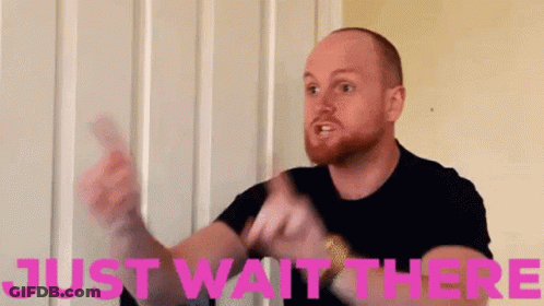 Bearded Man Holding Card Saying Just Wait There In Pink GIF