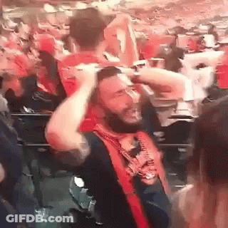 Bearded Man Holding Head In Crowd GIF