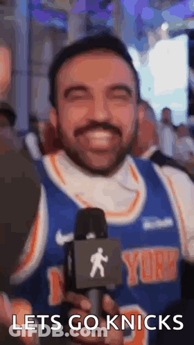 Bearded Man Holding Microphone Smiling In Knicks Jersey GIF