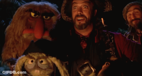 Bearded Man Holding Stuffed Animal In Front Of Muppets GIF