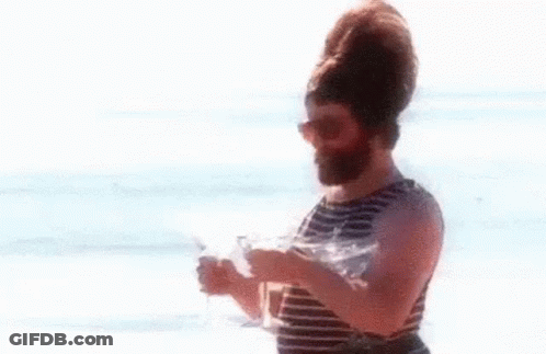 Bearded Man Holding Two Wine Glasses On Beach GIF