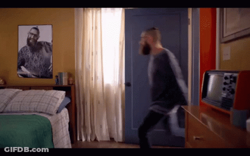 Bearded Man In Bedroom With Picture Of Man On Wall GIF