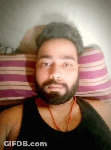 Bearded Man In Black Tank Top Laying On Striped Pillow GIF