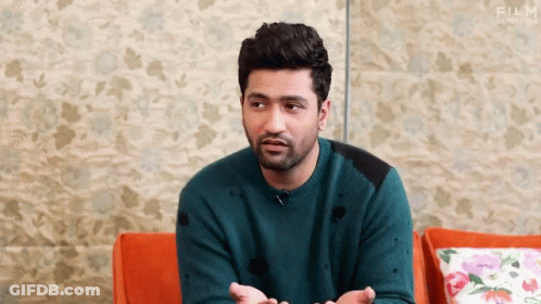 Bearded Man In Blue Sweater On Couch Hands Outstretched GIF