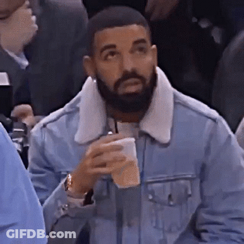 Bearded Man In Denim Jacket Holding Coffee In Crowd GIF