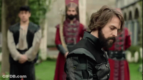 Bearded Man In Front Of Uniformed Men GIF