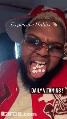 Bearded Man In Glasses And Red Jacket Holding Pills In Mouth GIF