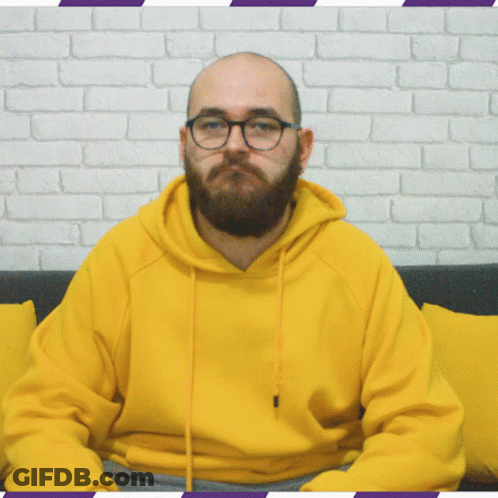 Bearded Man In Glasses And Yellow Hoodie Sitting On Couch GIF