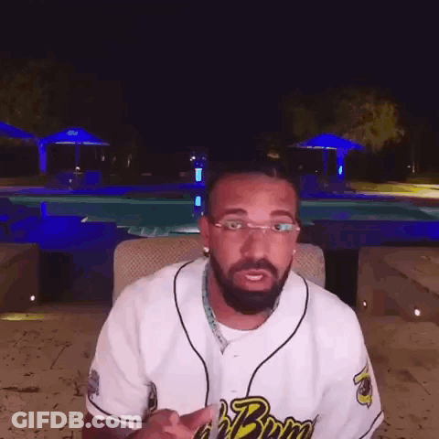 Bearded Man In Glasses Sitting By Pool At Night GIF