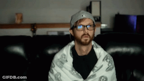 Bearded Man In Glasses Wrapped In Blanket On Couch GIF