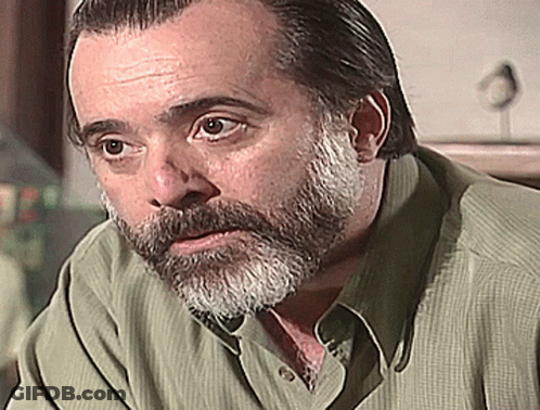 Bearded Man In Green Shirt Looking At Camera GIF