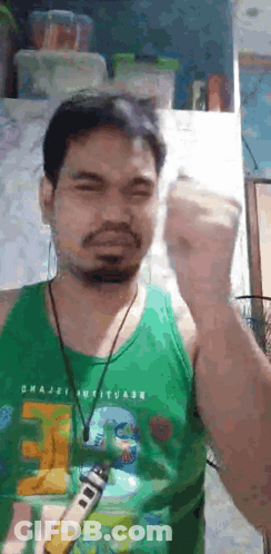 Bearded Man In Green Tank Top Holding Remote Control GIF